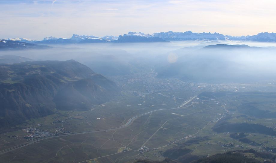 Beeld op de besneeuwde Dolomieten met in het dal (onder een inversie) Bolzano